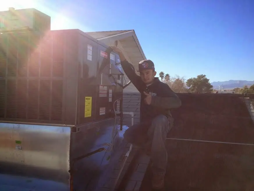 HVAC technician performing Air Duct Cleaning on a rooftop unit in Goodyear